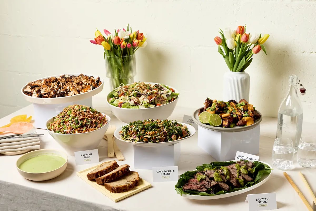 An atis catering spread of sharing bowls, salads, roast vegetables and sliced steak on a table